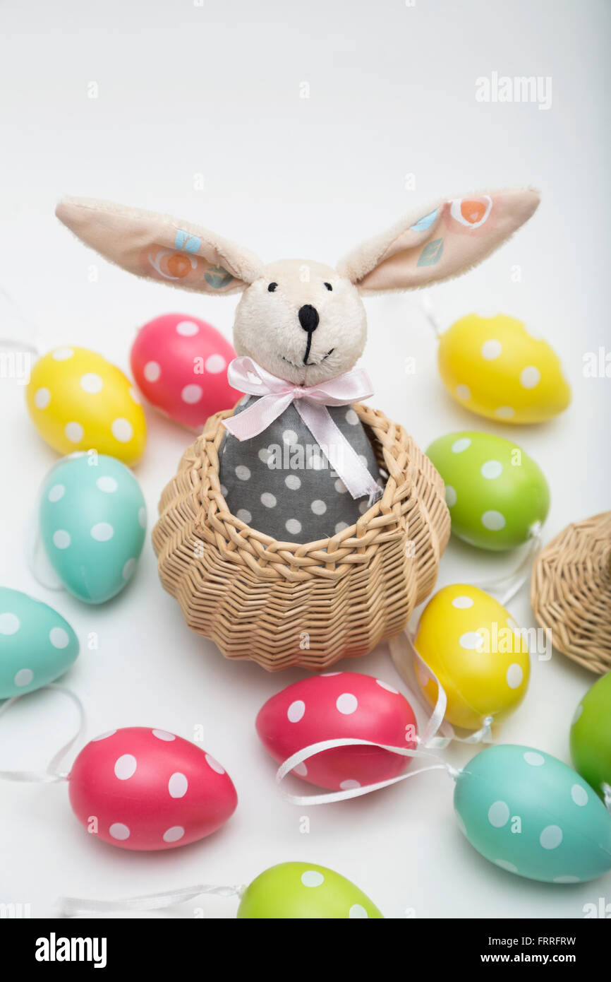 Toy Easter bunny in wicker basket with colorful dyed eggs Stock Photo ...