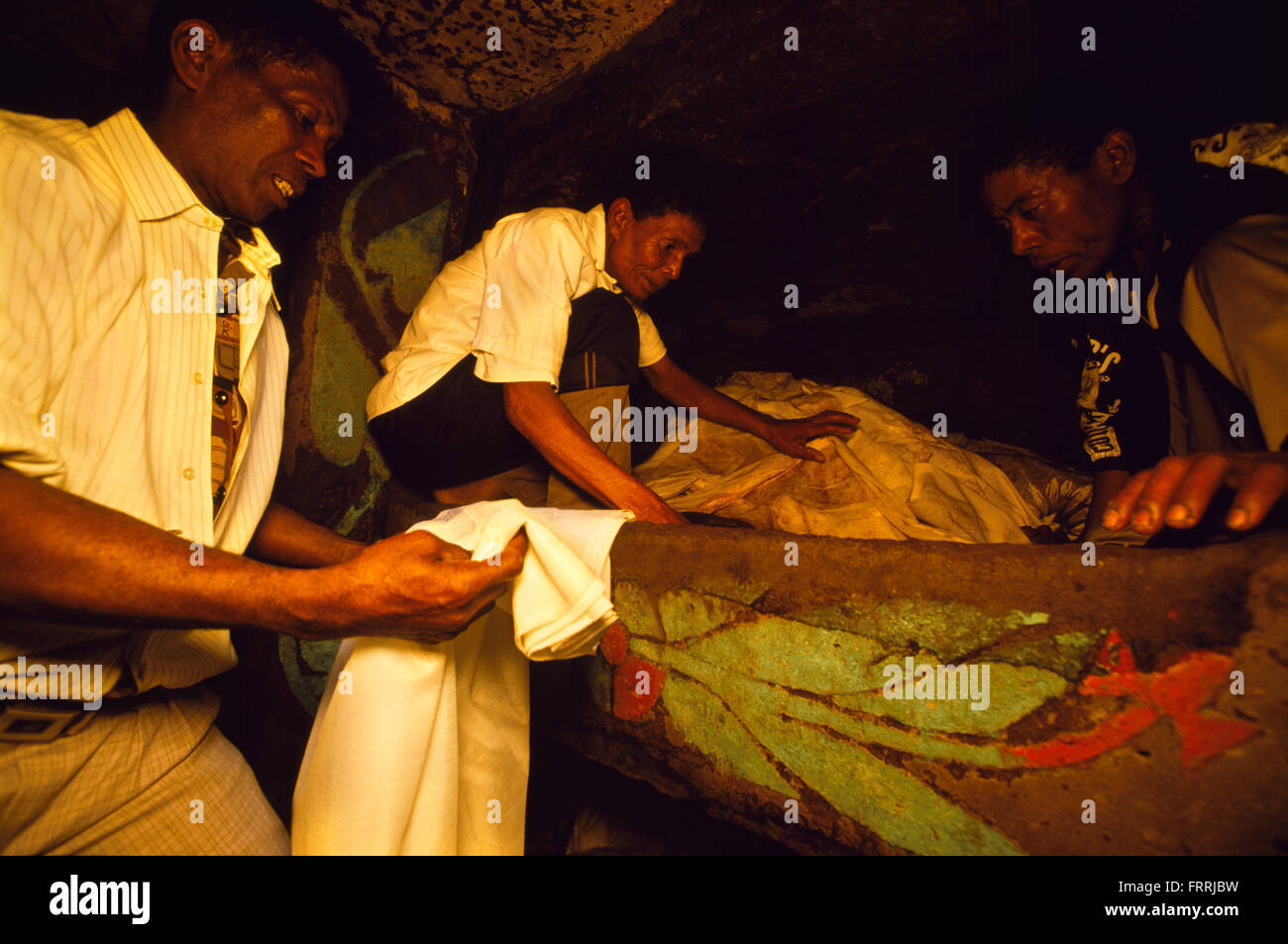 The male members of the family wrap the remains of the dead in new shrouds during a reburial ceremony in Madagascar Stock Photo
