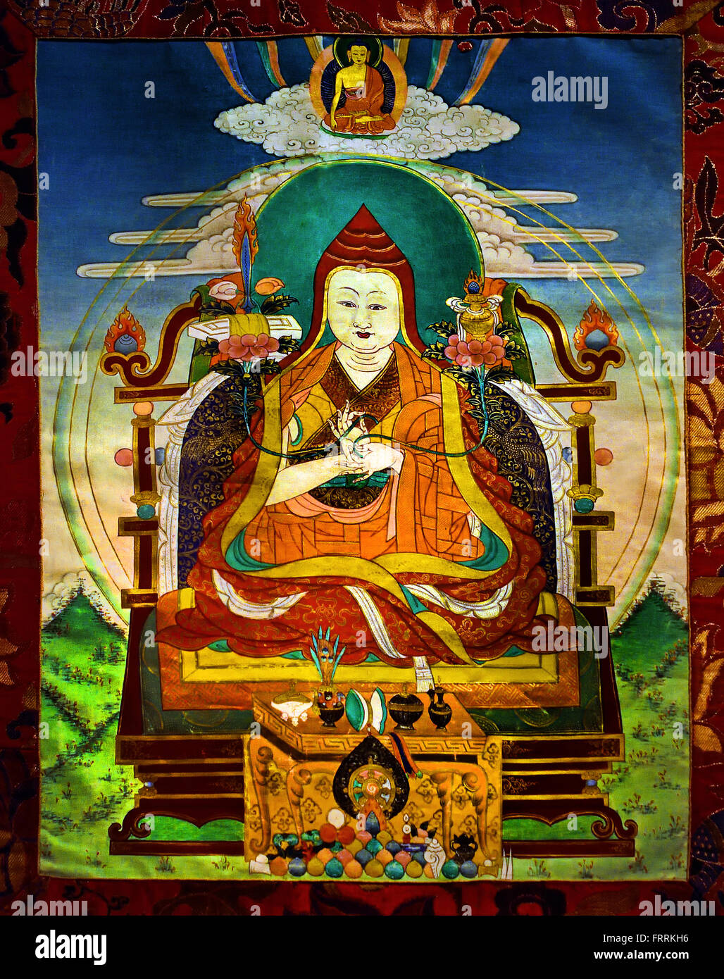 This scroll painting, thangka, shows a teacher, Lama, on a throne with his hands in dharmacakramudra. In each of his hands he holds a lotus stem .  Tibetan Tibet China Stock Photo