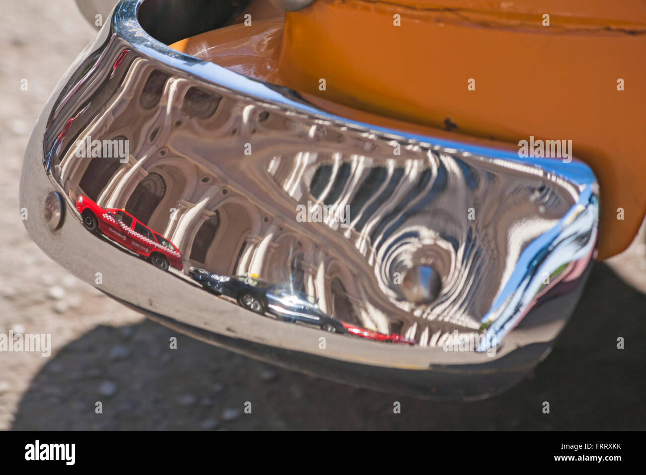 Distorted reflections of cars and buildings in front bumper of yellow chevrolet car at Havana, Cuba Stock Photo