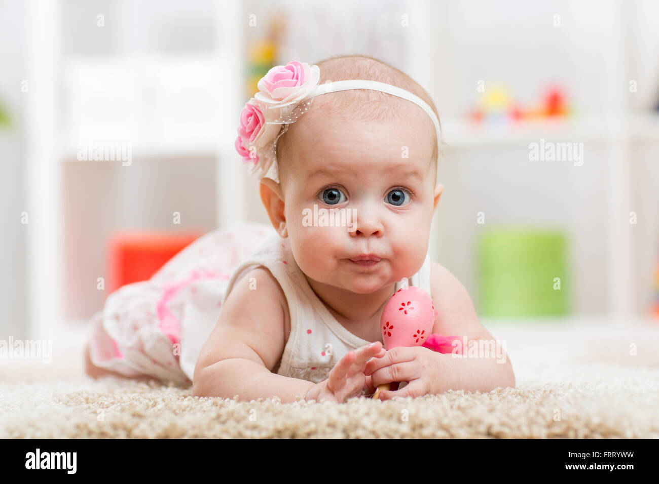 Portrait of adorable baby girl lying on fluffy carpet Stock Photo