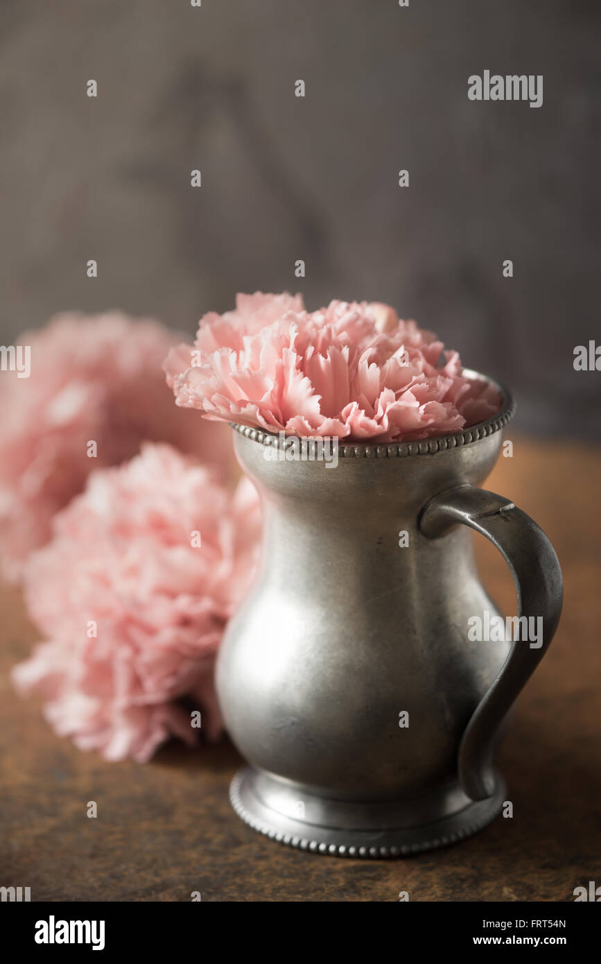 Carnation in the metal vase on the stone table Stock Photo