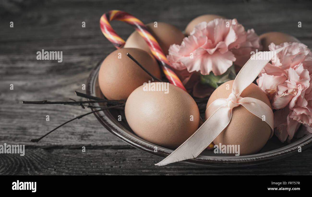 Eggs with ribbon , branches , flowers and candy on the wooden table horizontal Stock Photo