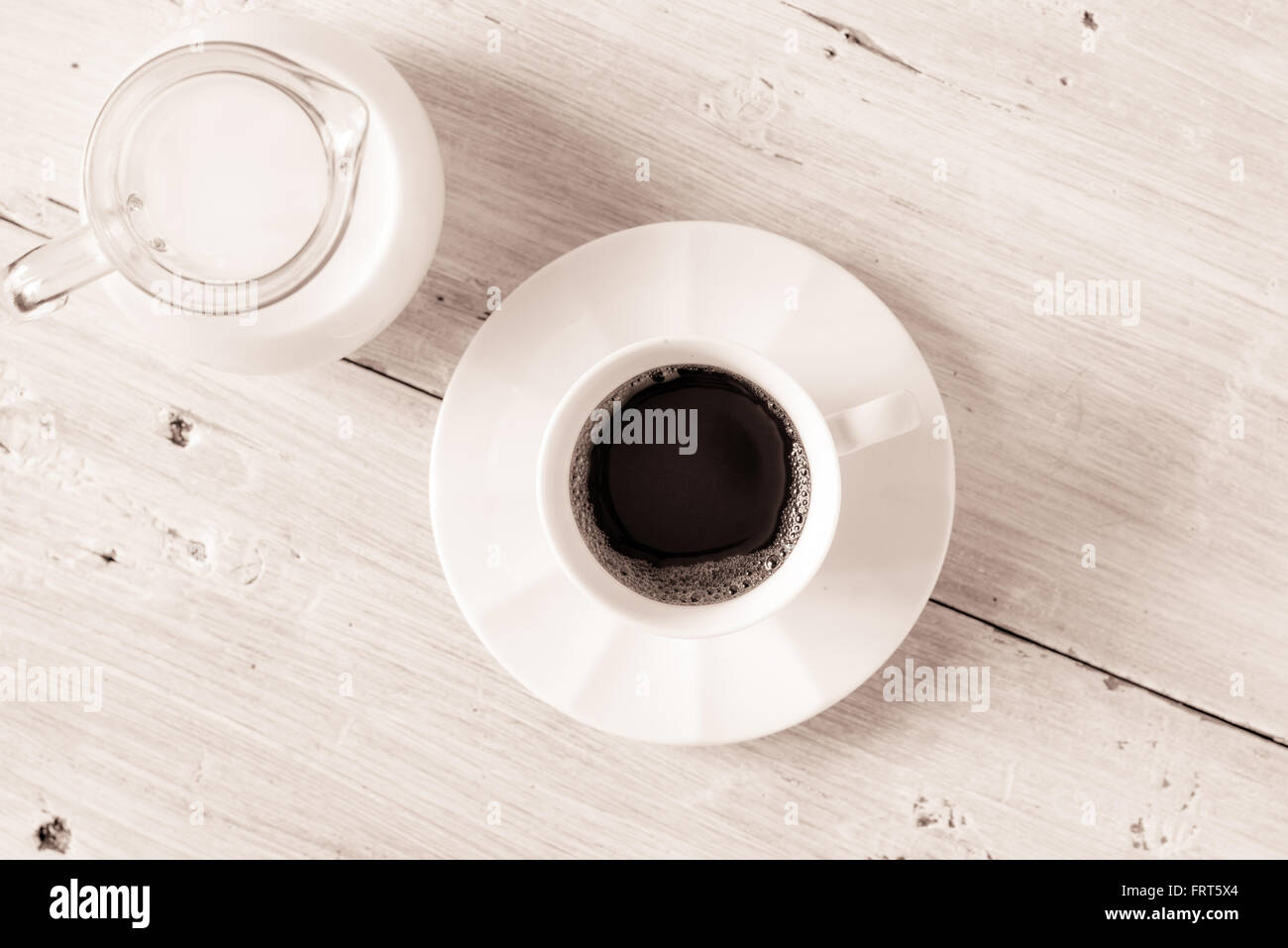 Cup of coffee with jug of milk on the white table top view Stock Photo