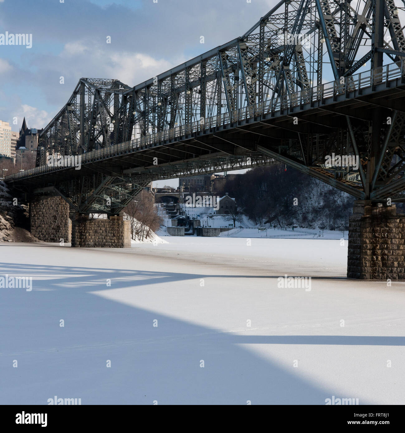 Locks of the Rideau Canal are framed by the Alexandra bridge and a frozen Ottawa River. Stock Photo