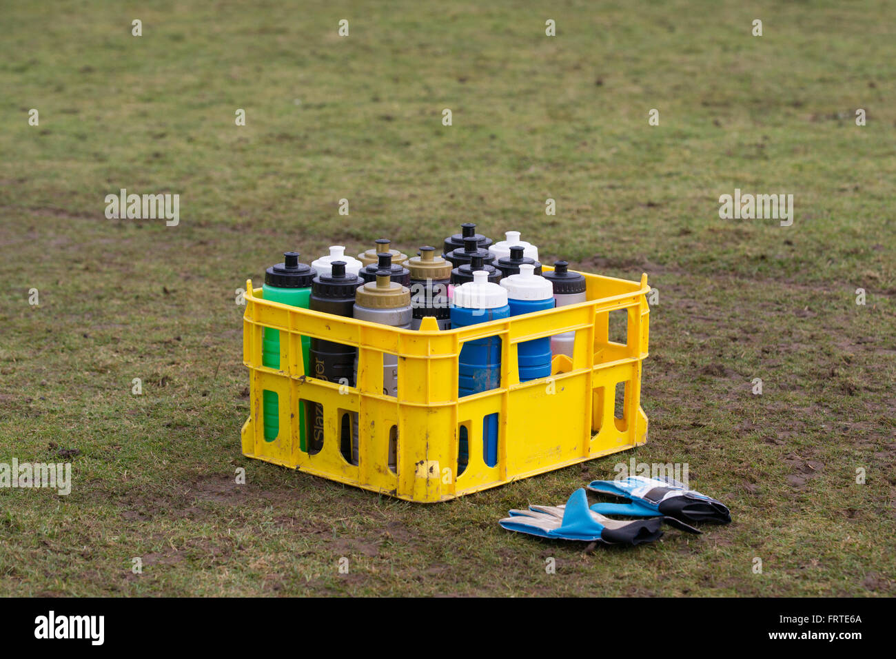 Coloured crate of water bottles with gloves beside football pitch Stock Photo