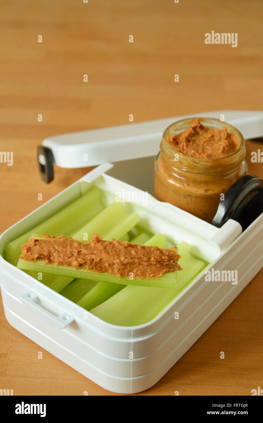 Healthy snacks - snack box containing stalks of celery and jar of peanut butter. Stock Photo