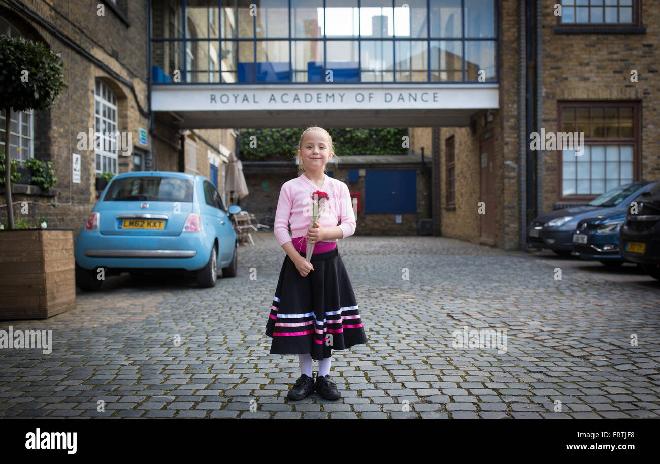 A young girl poses with a red rose following her grade 1 ballet examination outside the Royal Academy of Dance in London Stock Photo