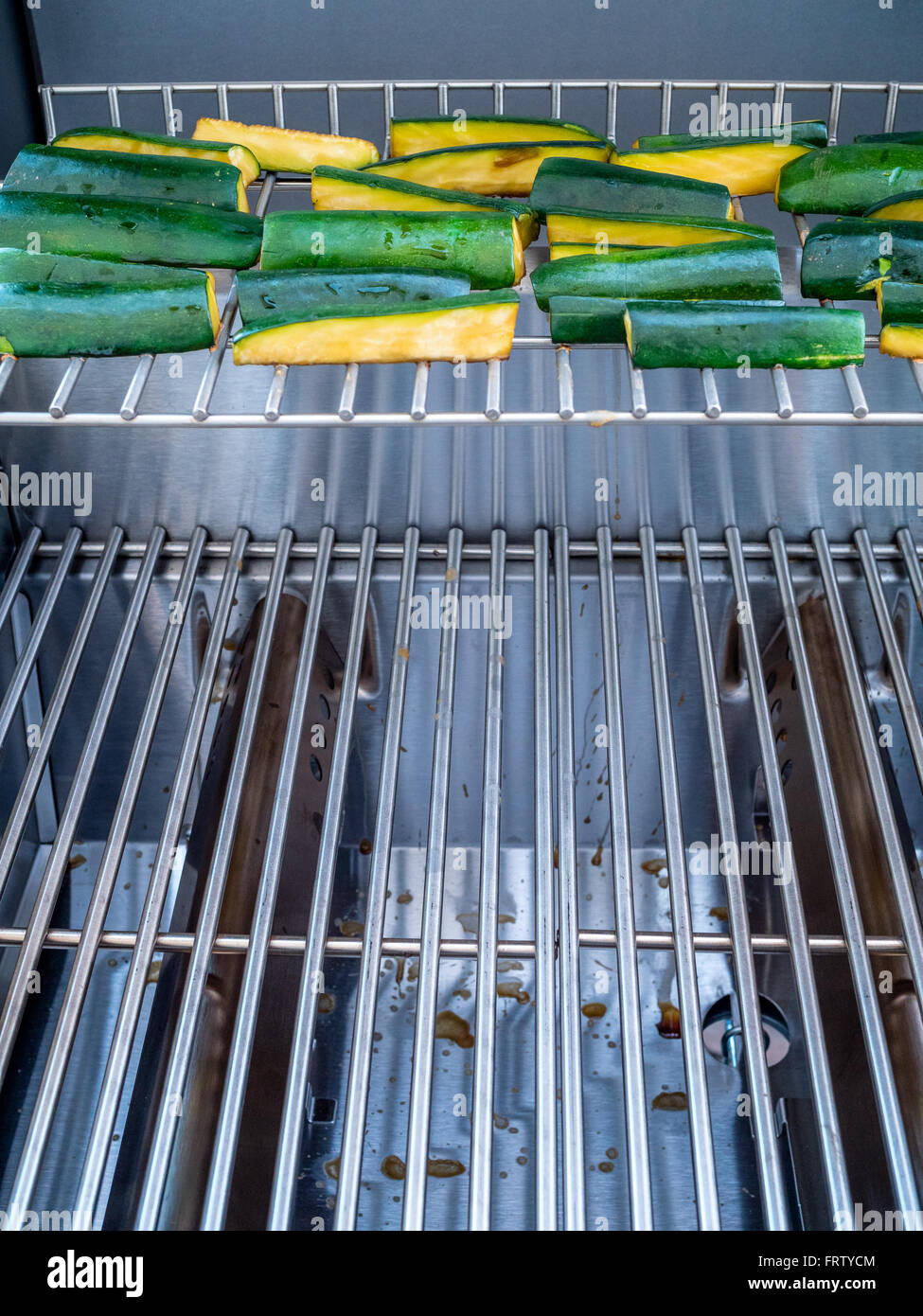 Green zucchini cooking on stainless steel bar b que Stock Photo