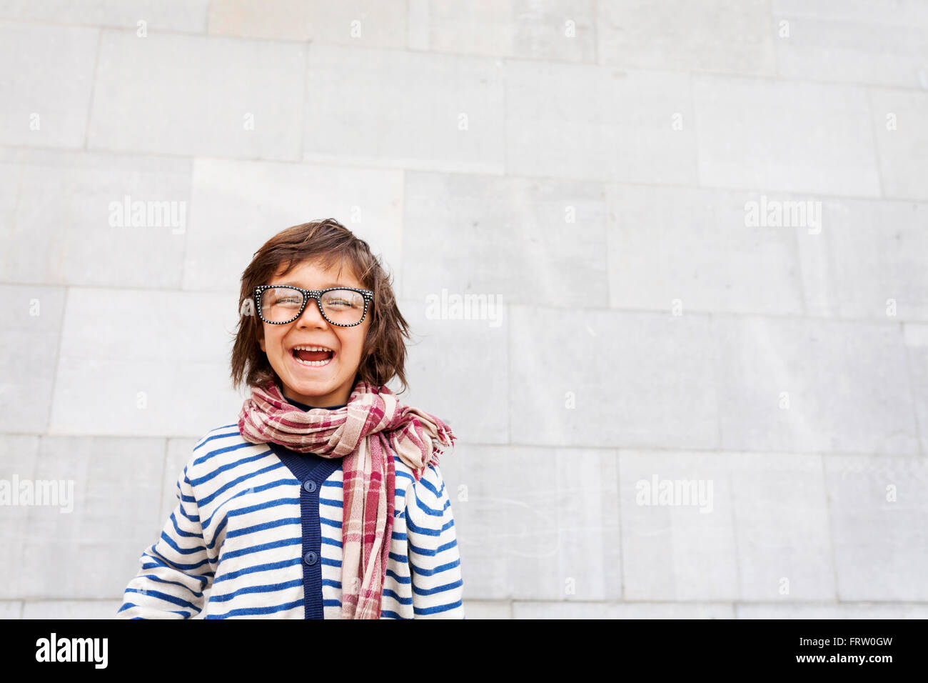 Portrait of laughing little boy wearing scarf and oversized glasses Stock Photo