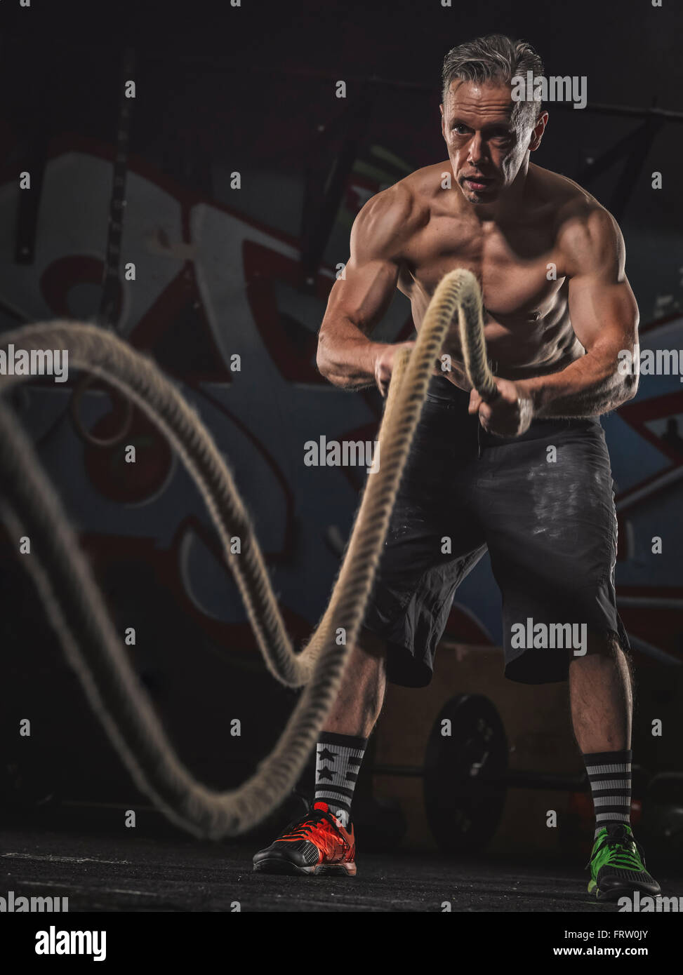 Mature crossfit athlete exercising with ropes Stock Photo