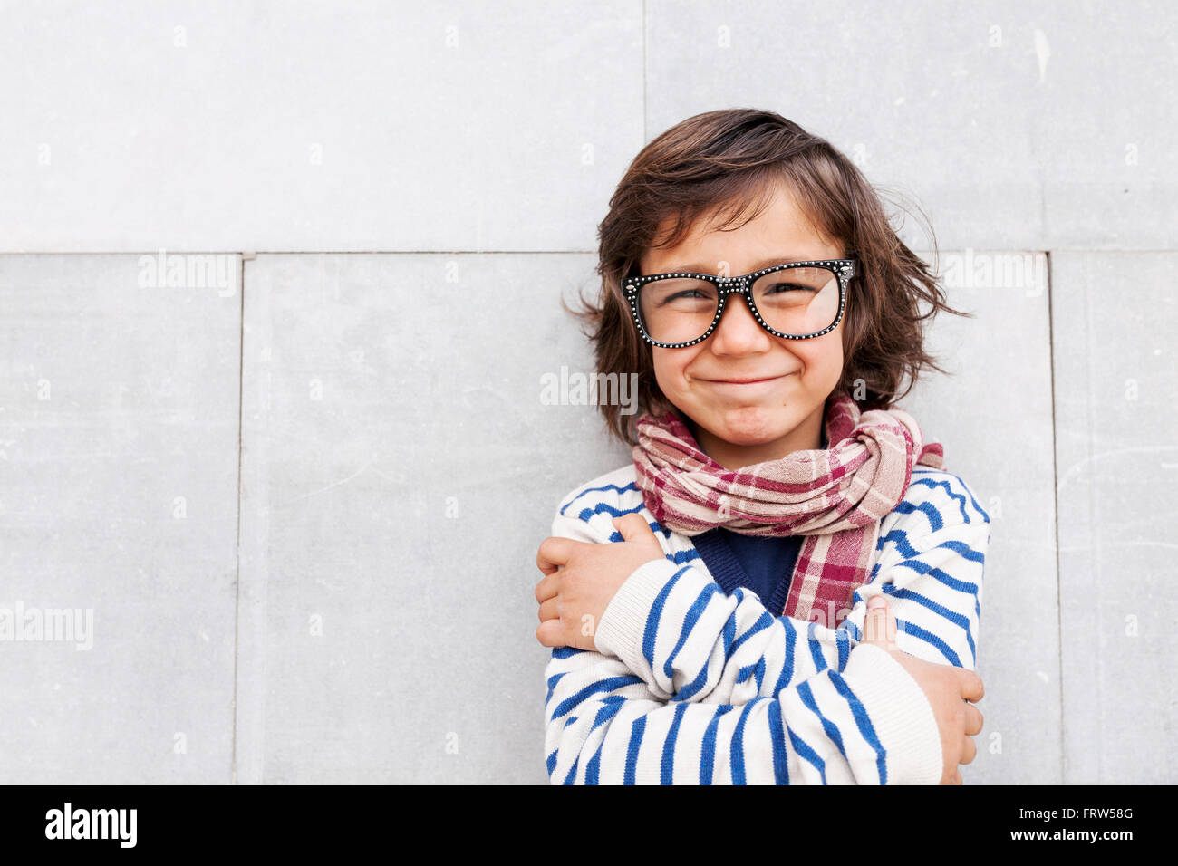 Portrait of grinning little boy wearing scarf and oversized glasses Stock Photo