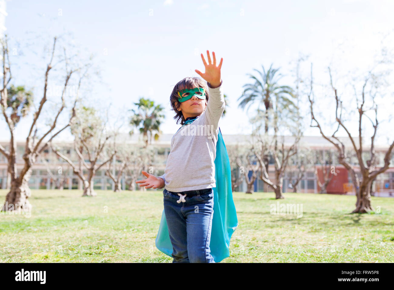 Little boy dressed up as a superhero posing on a meadow Stock Photo