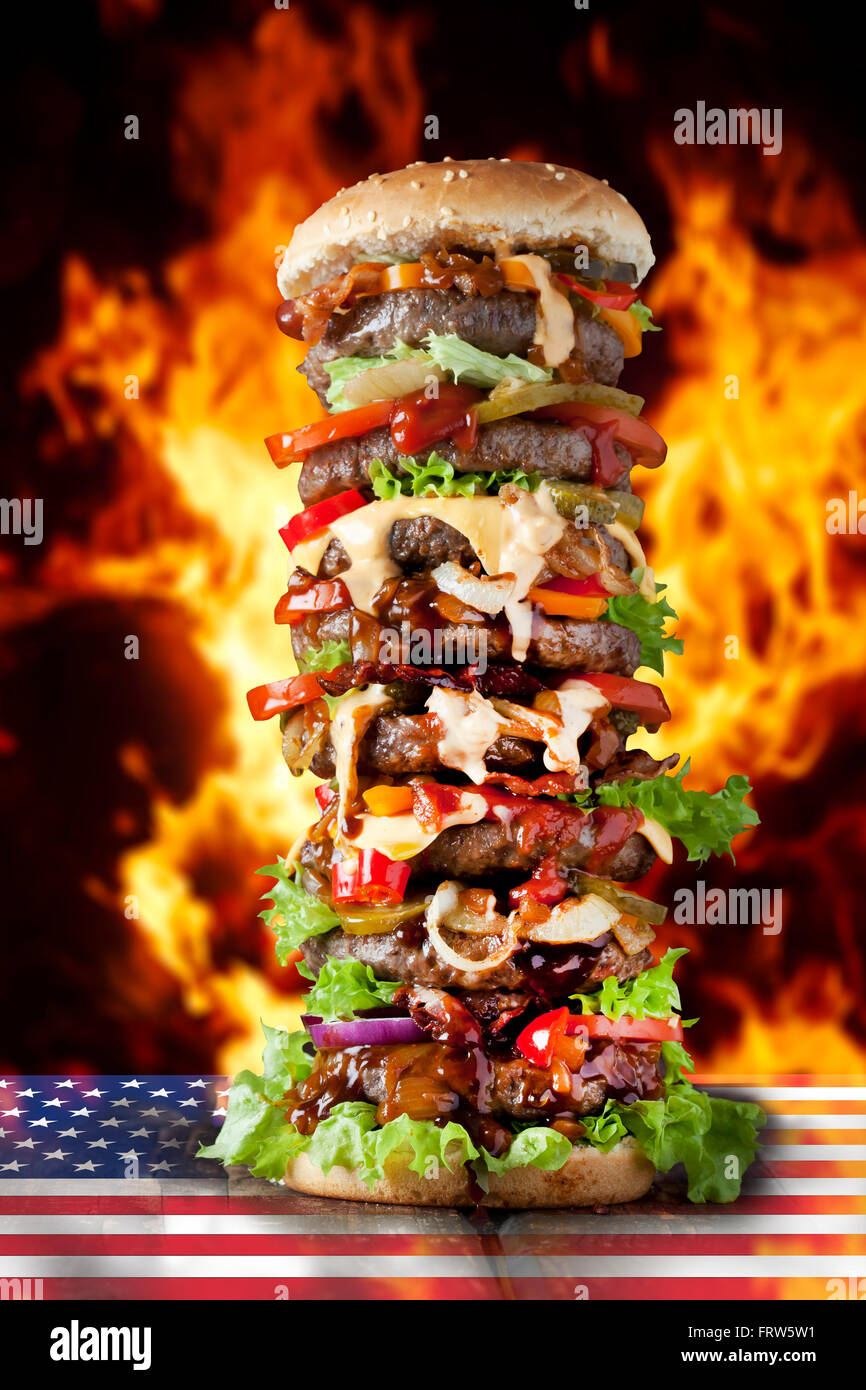 Extra large hamburger on US flag against burning flalmes Stock Photo ...