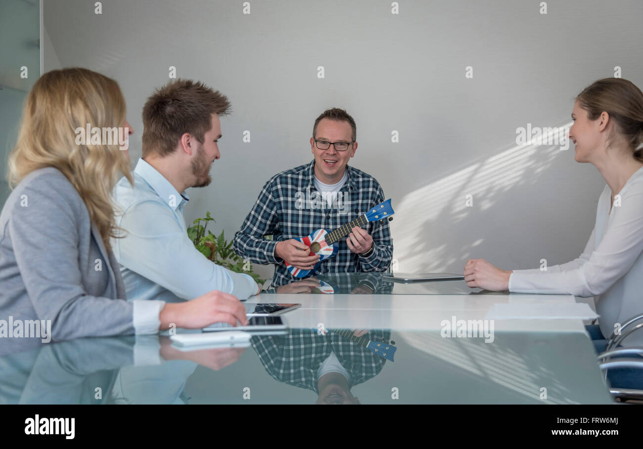 Colleagues having a meeting with man playing banjo Stock Photo