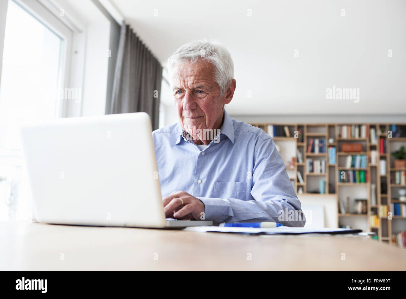 Portrait of senior man sitting at table using laptop Stock Photo