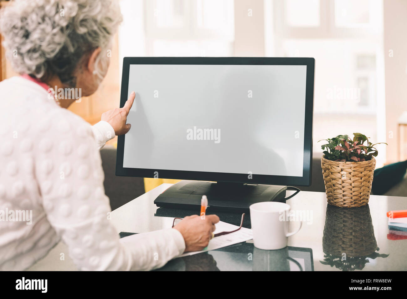 Over the shoulder shot of elderly woman using a desktop computer at home Stock Photo