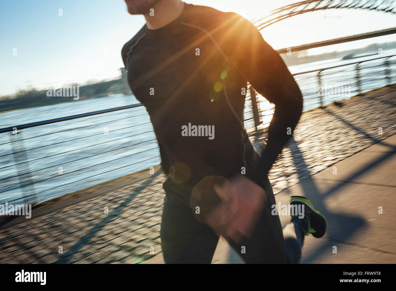 Germany, Cologne, Young man running at the riverside Stock Photo