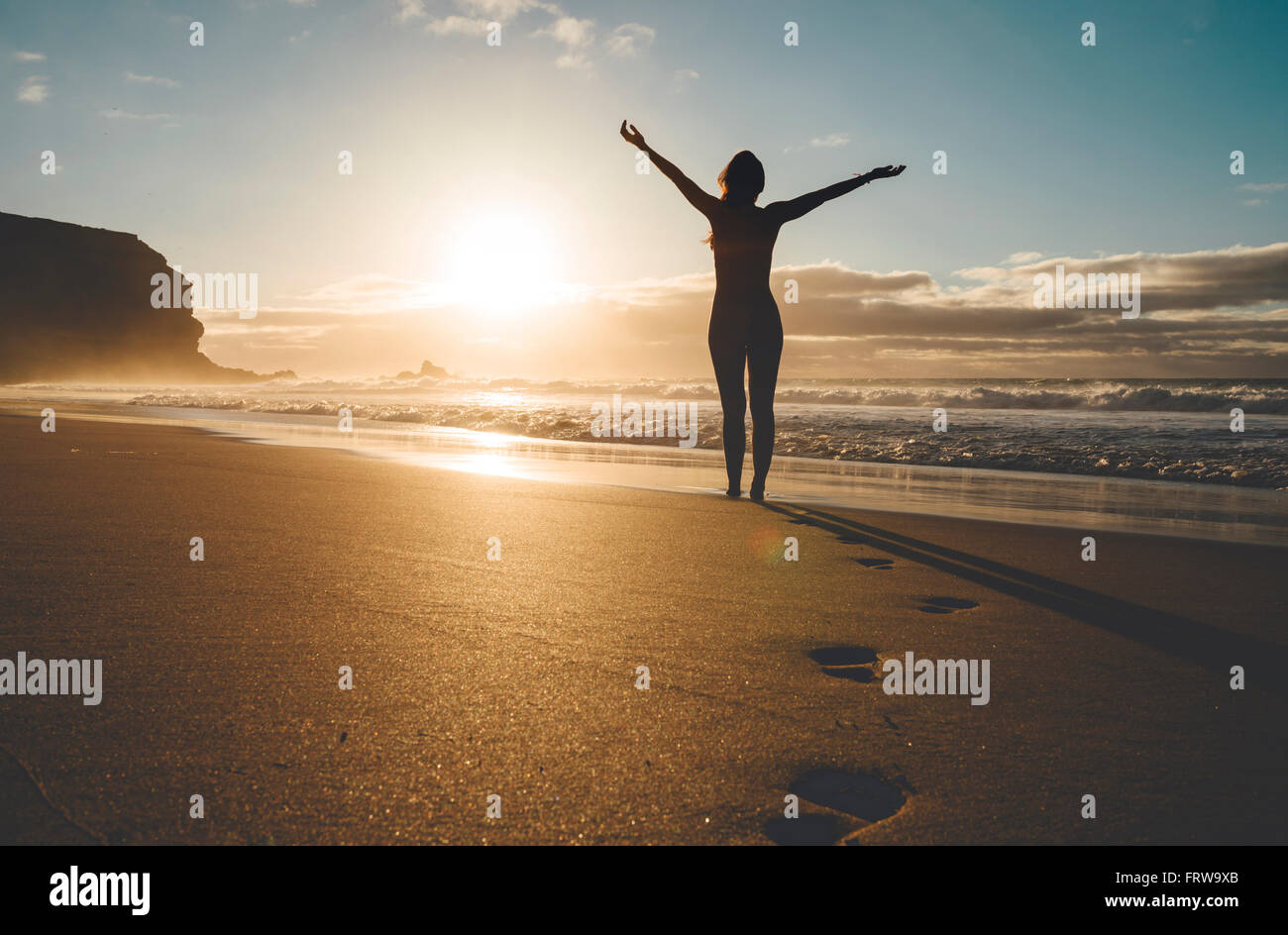 Woman standing on the beach with raised arms at sunset Stock Photo - Alamy