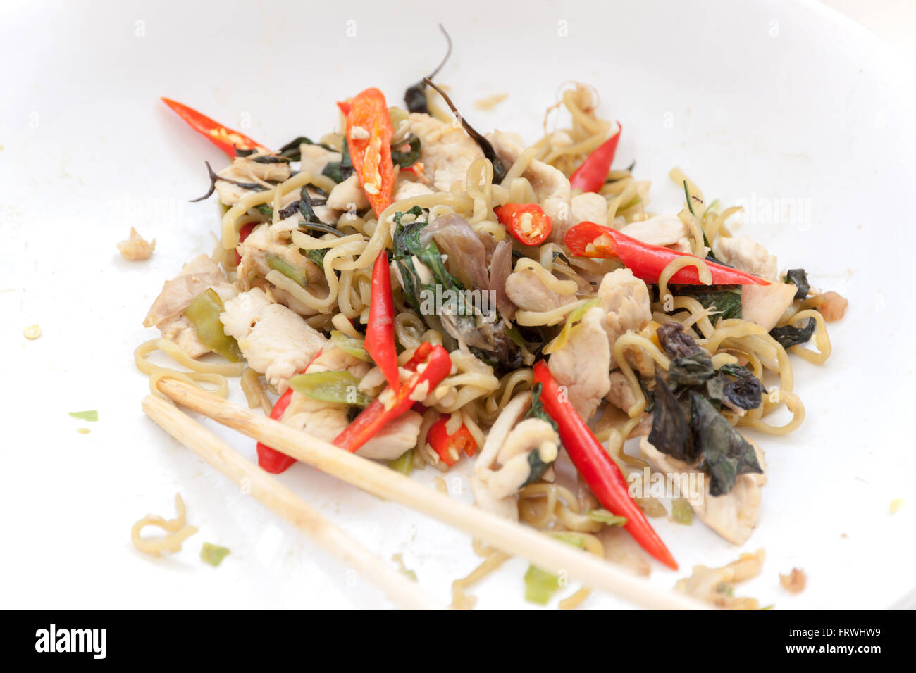 Chinese noodles fried with spicy chicken in white plate. Stock Photo