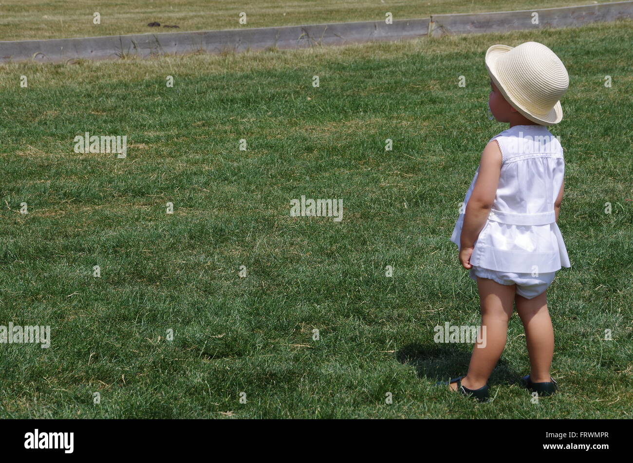 Little girl in elegant white summer dress looking away Stock Photo