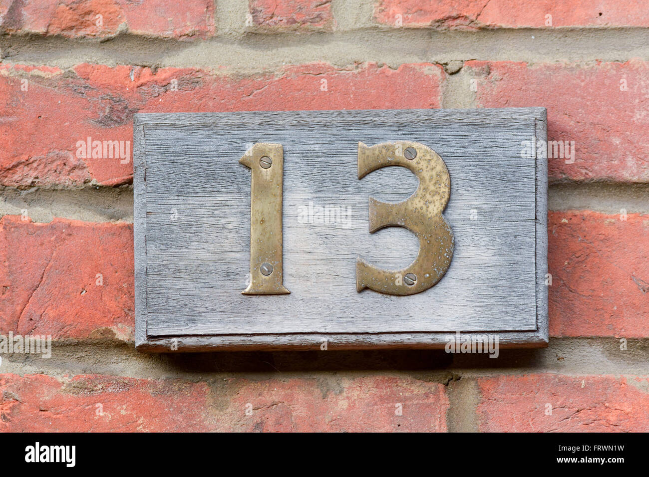 House number 13 sign with brass numbers on wooden plinth Stock Photo