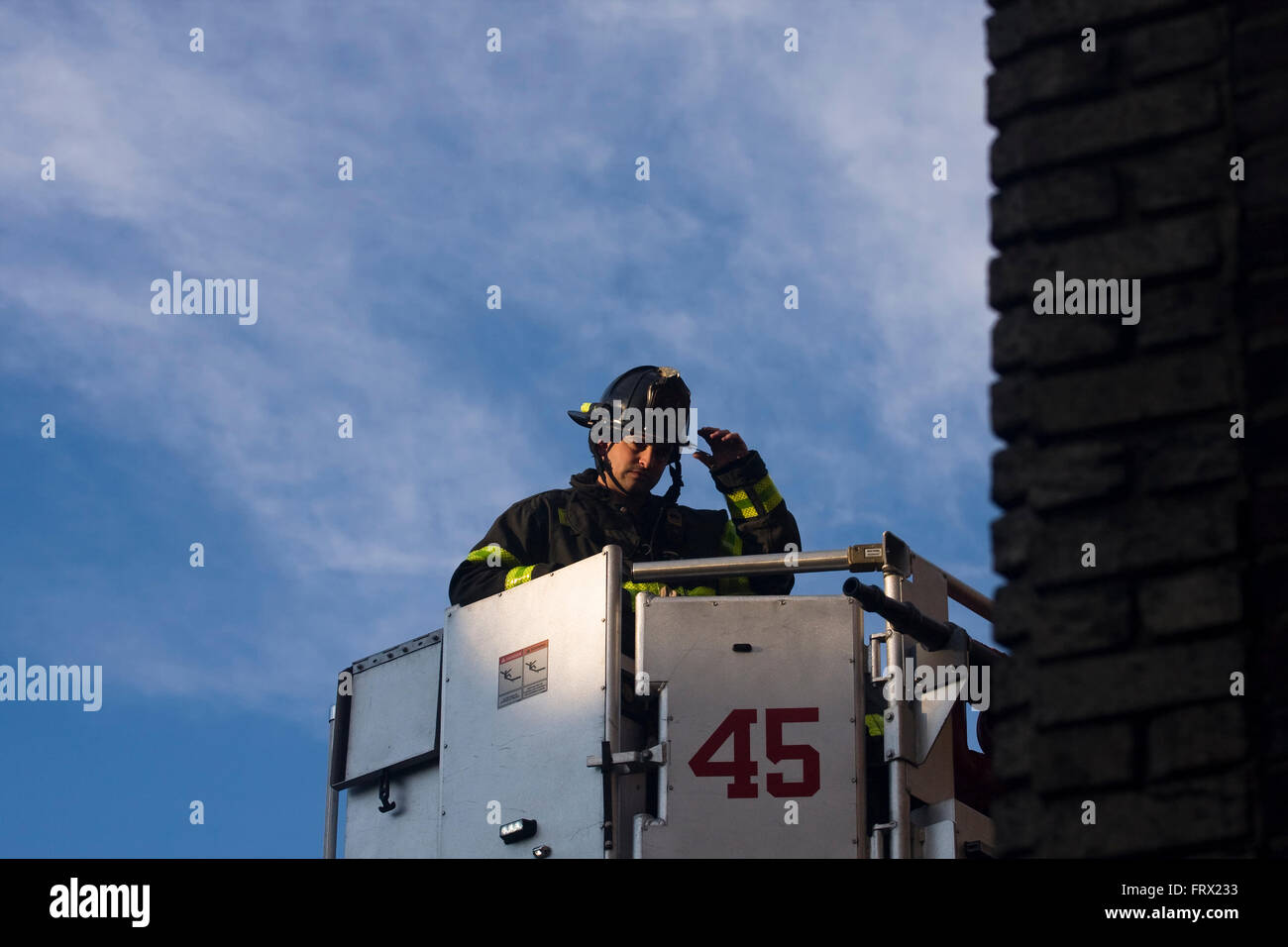 A Firemen from Engine 45 in Manhattan being lifted inside an aerial platform ladder truck's bucket whilst responding to a call Stock Photo