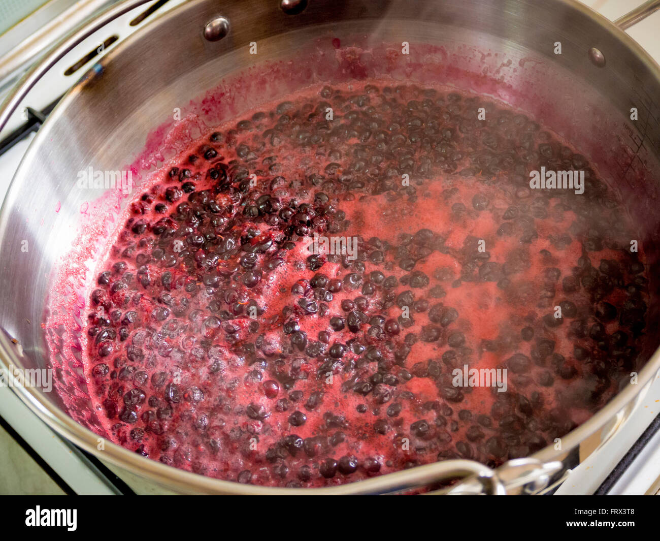 Jam Making at home - Blackcurrants in large Maslin Pan boiling on stove Stock Photo