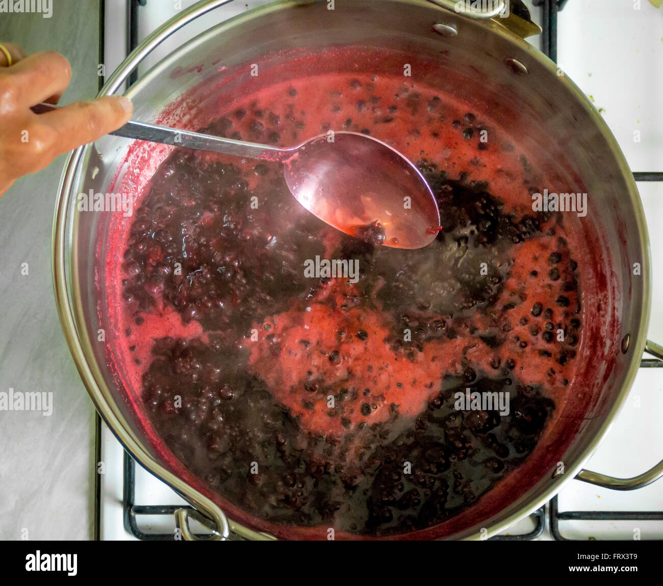 Jam Making at home - Blackcurrants in large Maslin Pan boiling on stove Stock Photo