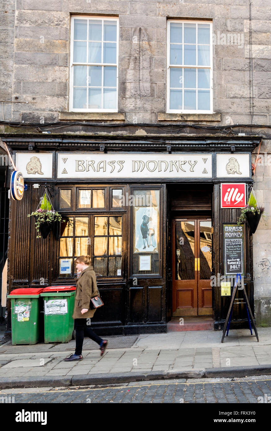 A young woman walking past the Brass Monkey pub in Edinburgh. Stock Photo