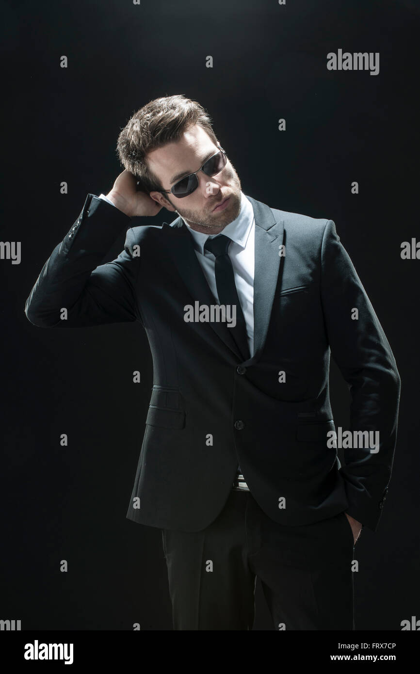 handsome man in black suit on a black background Stock Photo - Alamy