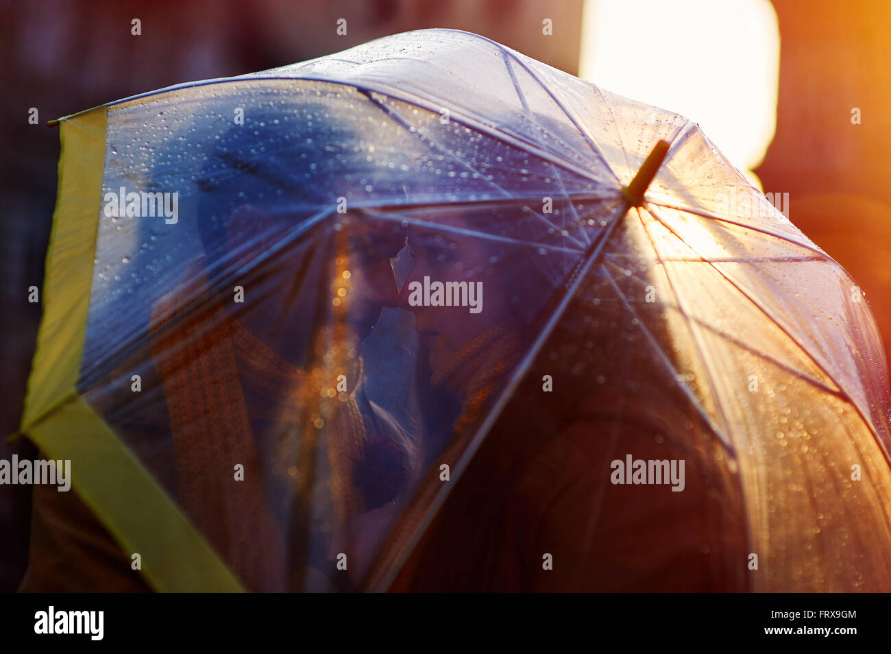 Closeup of young beautiful couple kissing under umbrella Stock Photo