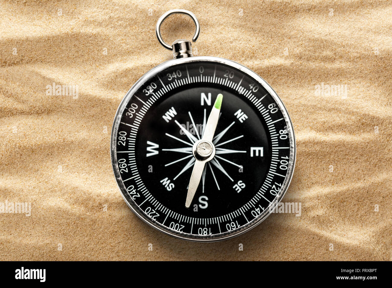 Black compass on the sand background closeup Stock Photo