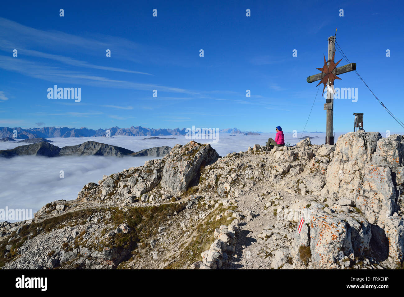 Woman sitting at summit of Guffert, mountain range in background, Brandenberg Alps Rofan, Tyrol, Austria Stock Photo