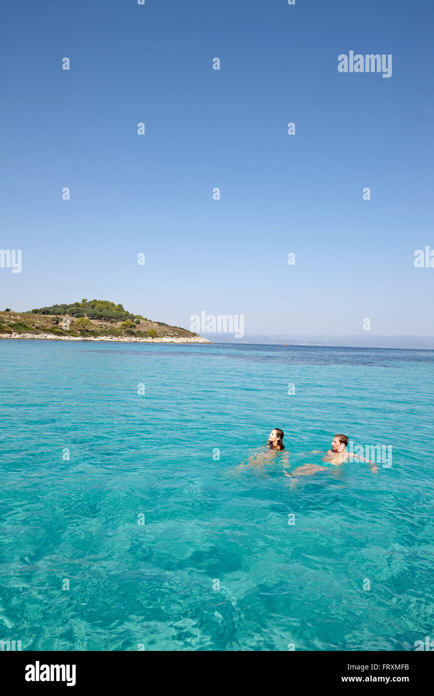 Couple swimming in Blue Lagoon, Vourvourou, Sithonia, Chalkidiki, Greece Stock Photo