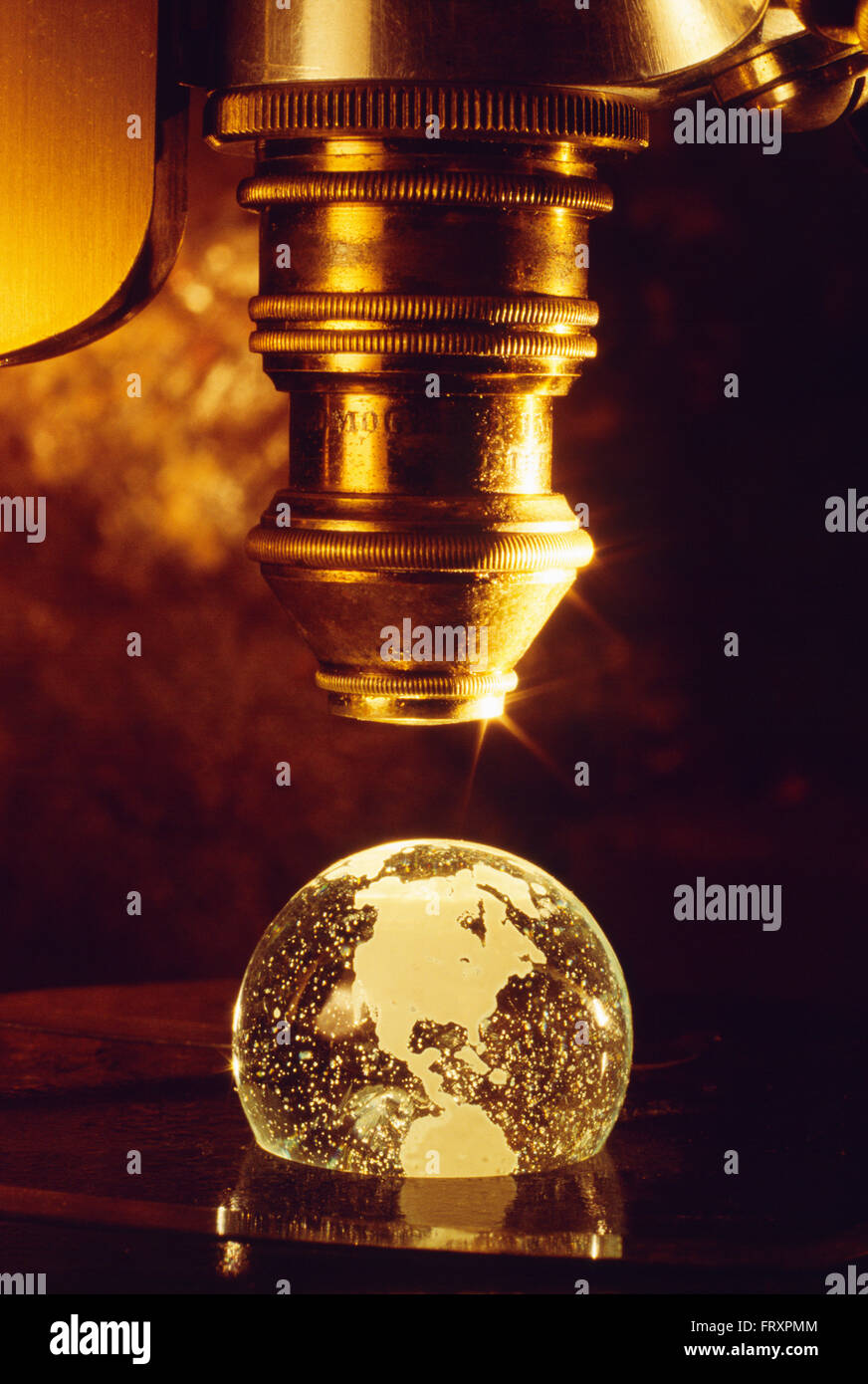 Close-up of an Antique Microscope Objective Viewing an Earth Globe Stock Photo