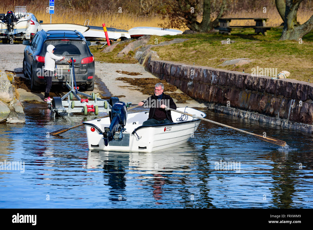 Torhamn, Sweden - March 18, 2016: The launching of a small plastic motor boat at a ramp in the marina. Boat is rowed by man afte Stock Photo