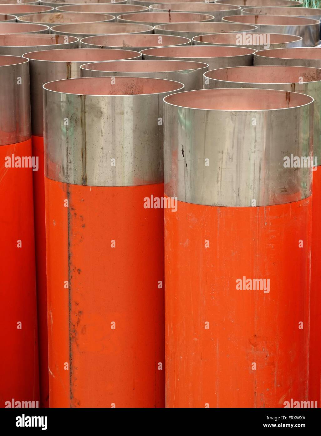 Large orange PVC pipes with stainless steel metal caps Stock Photo