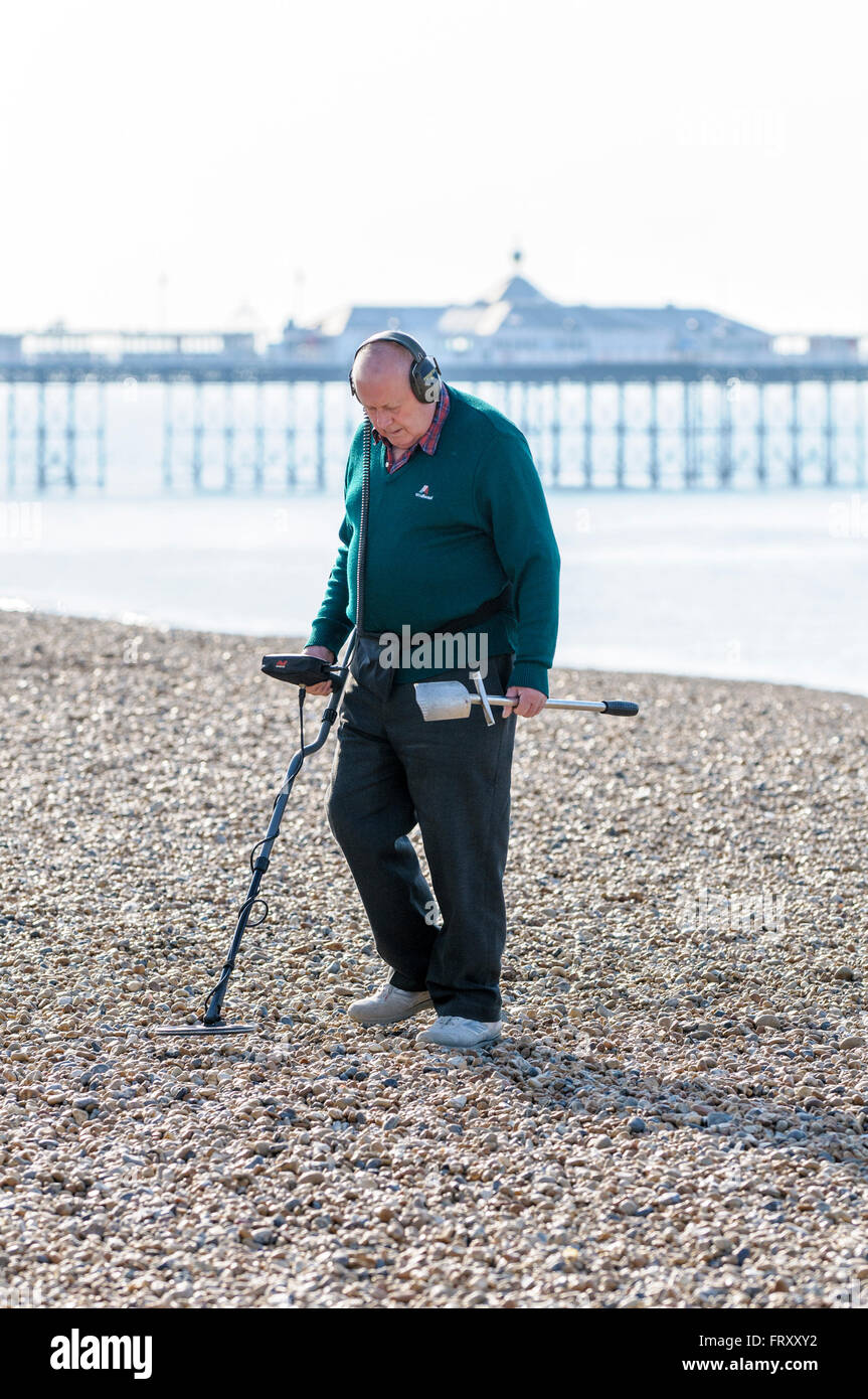 Senior man metal detecting on Brighton beach, East Sussex, England, UK