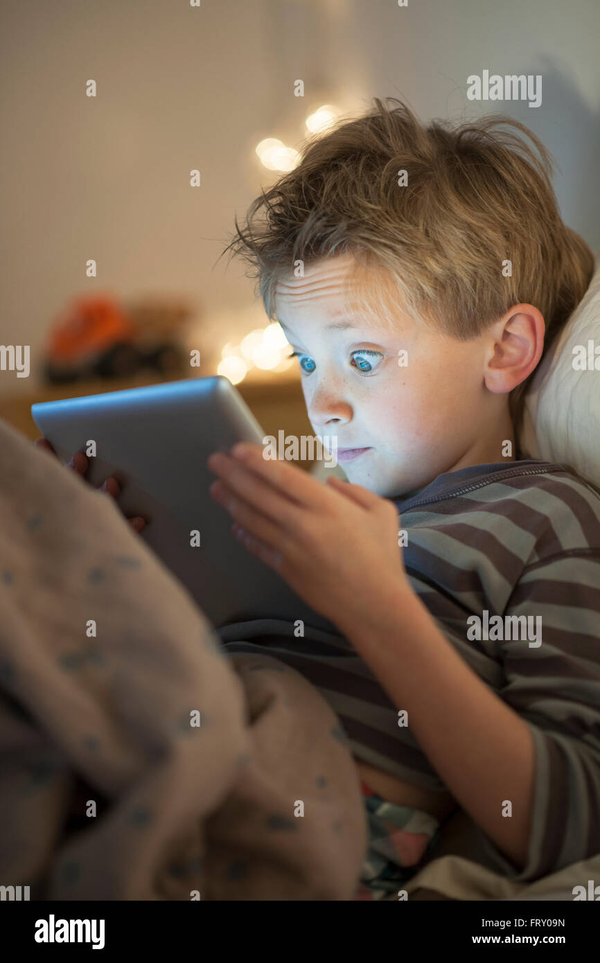 little boy at expressive face using a digital tablet in bed Stock Photo ...