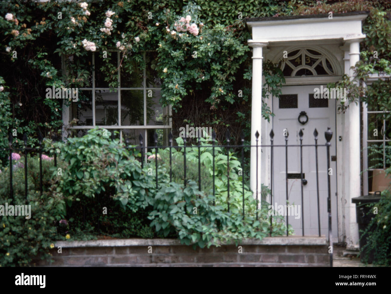 Wrought iron railings on front garden of townhouse with a white front door and porch Stock Photo