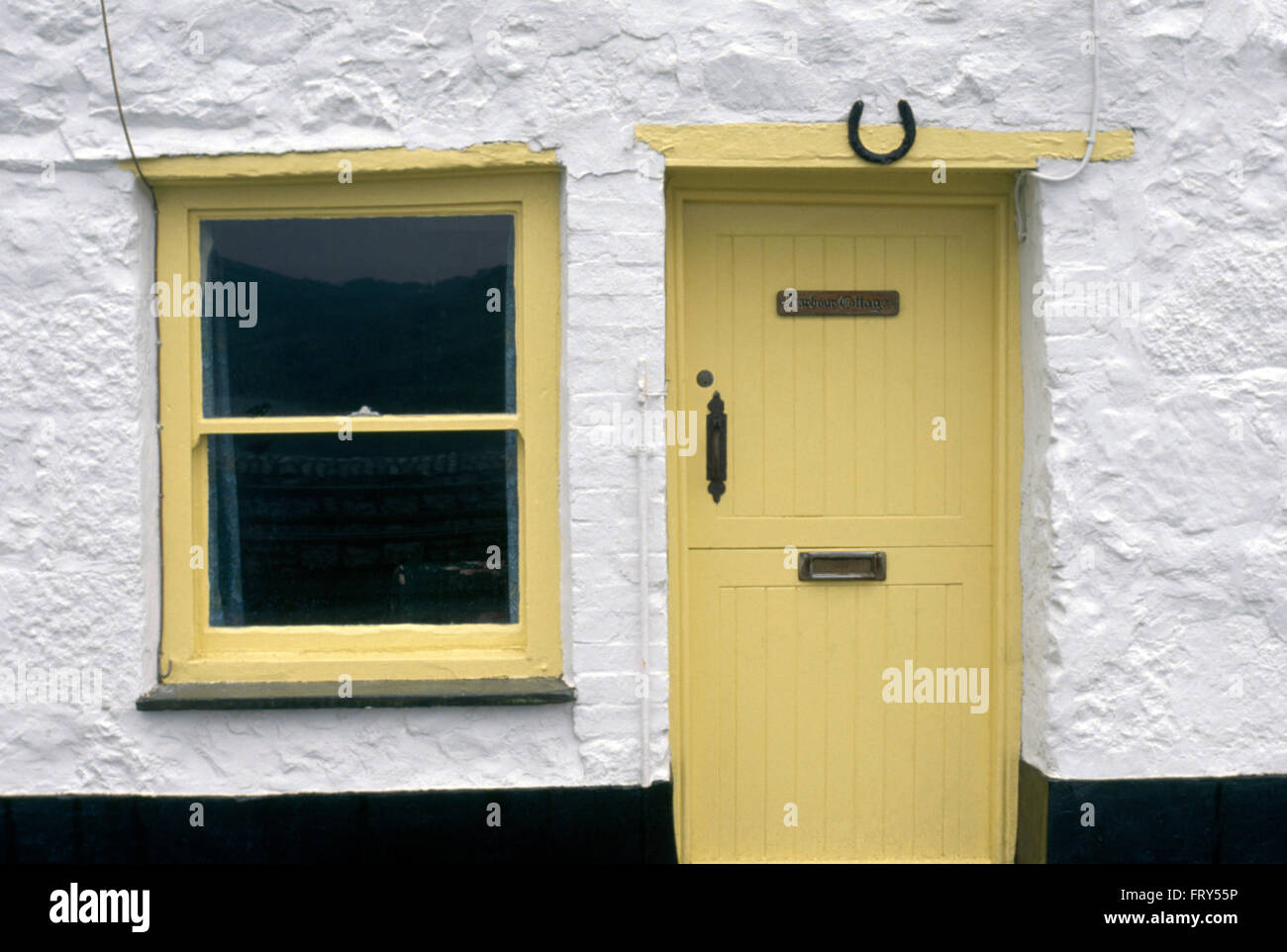 Close-up of a white coastal cottage with pale yellow front door and window Stock Photo