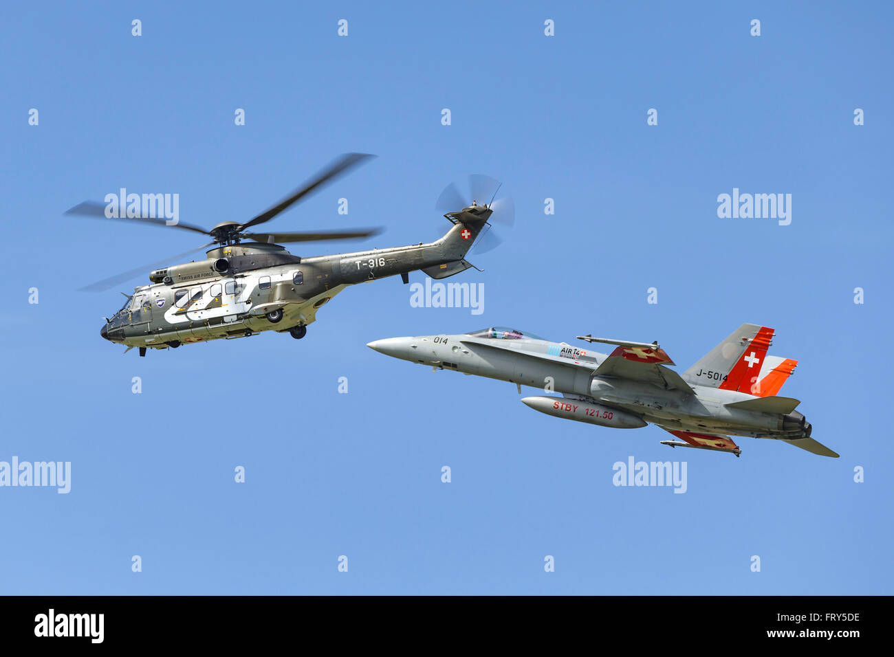 Aerospatiale Super Puma Military helicopter T-316 from the Swiss Air Force flies in formation with an F/A-18C Hornet fighter Stock Photo