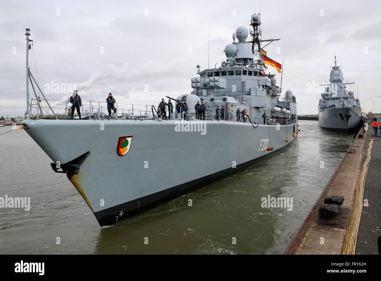 Wilhelmshaven, northern Germany, March 24, 2016: The frigate F213 "Augsburg" of the German Navy is pictured at the Navy port of Wilhelmshaven. The vessel returns from a mission in the Persian Gulf where it supported the French aircraft carrier "Charles de Gaulle" in the Operation "Counter Daesh MAR" against the IS in Syria and Iraq. -- Wilhelmshaven, Deutschland, 24. Maerz 2016: Die Fregatte F213 "Augsburg" der Bundesmarine faehrt im Marinehafen von Wilhelmshaven an ihren Liegeplatz. Das Schiff kehrt nach mehrmonatigem Einsatz aus dem Persischen Golf zurueck, wo es den franzoesischen Flugzeugt Stock Photo