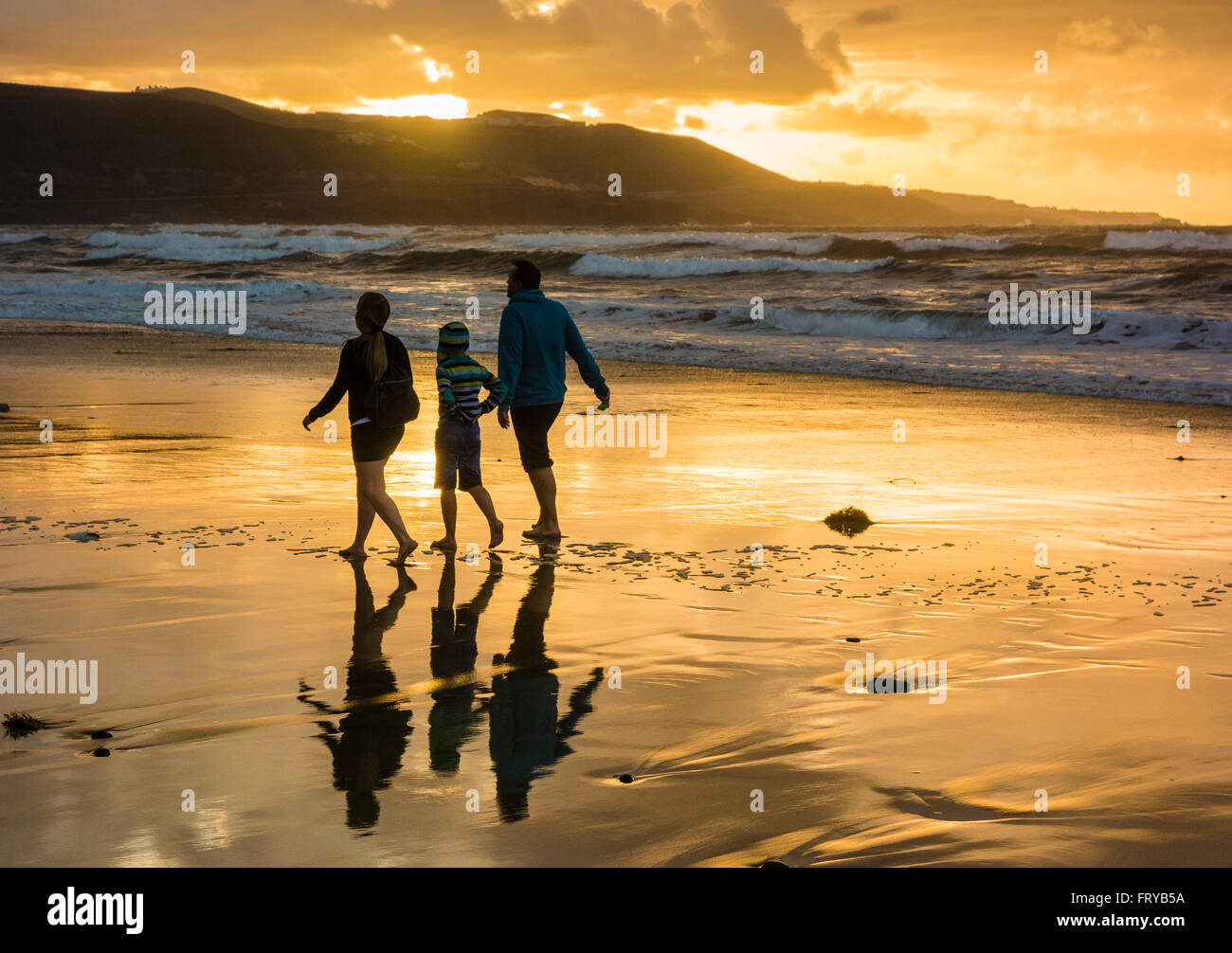 Las Palmas, Gran Canaria, Canary Islands, Spain, 24th March 2016. Weather: A family walking on the beach as the sun sets over Las Canteras beach in Las Palmas on Gran Canaria on a glorious Thurdsay in the Canary Islands; the day Prime Minister David Cameron and family arrived in the Canary Islands (Lanzarote) for their Easter holiday. Credit:  Alan Dawson News/Alamy Live News Stock Photo