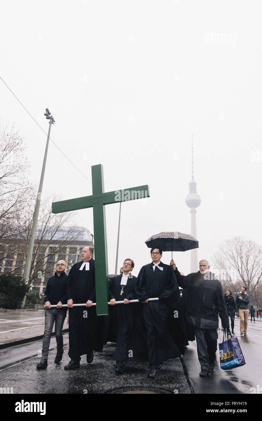 Berlin, Germany. 25th March, 2016. Syrian refugee JALAL AL DEBES, Superintendent BERTOLD HÃ–CKER, Bishop MARKUS DRÃ–GE and Pastor GREGOR HOHBERG carrying a large green cross during Good Friday procession in Berlin. Credit:  Jan Scheunert/ZUMA Wire/Alamy Live News Stock Photo