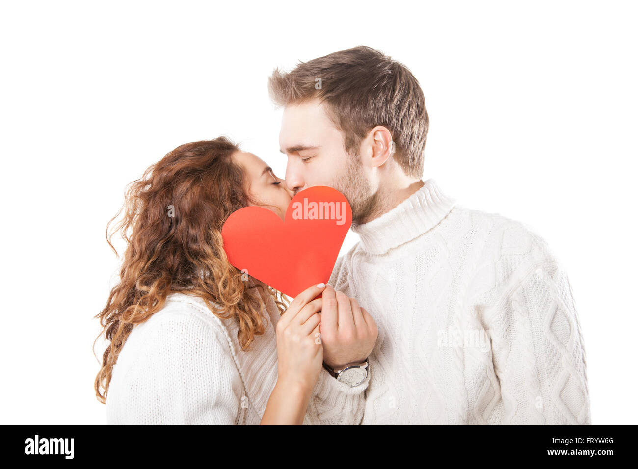 Happy couple kissing behind a red heart Stock Photo - Alamy