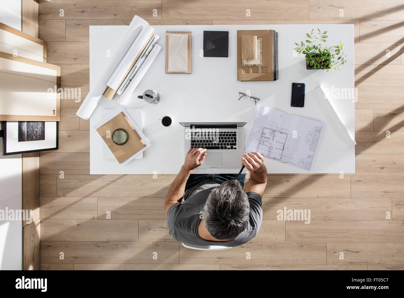 top view, architect sitting at desk and working on his laptop, there is