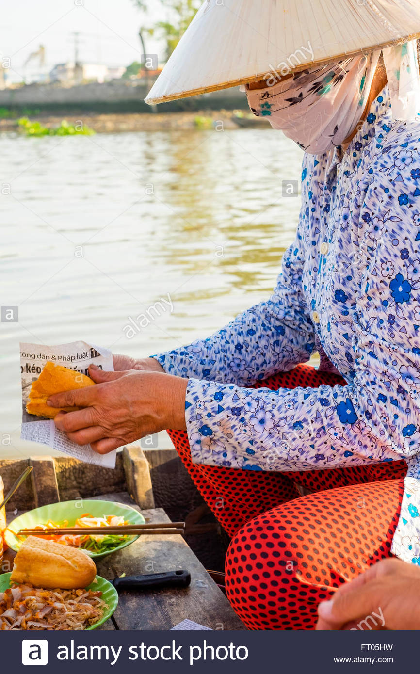 A Vietnamese woman prepares Banh mi sandwiches at Phong Dien floating market, Phong Dien, Can Tho, Mekong Delta, Vietnam Stock Photo