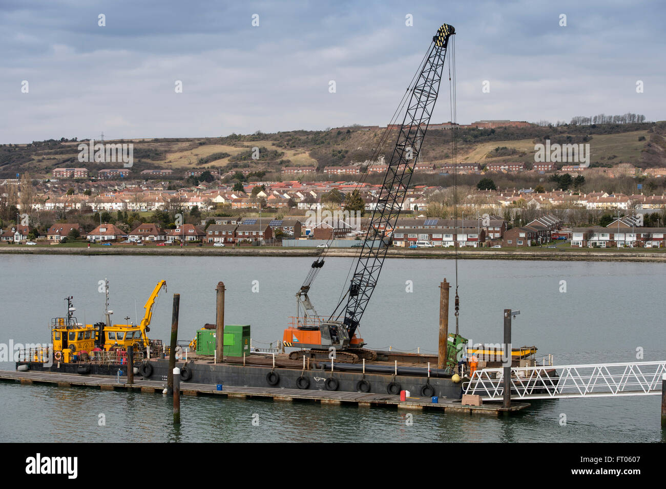 Barge with pile driver constructing pontoons on the coast. Stock Photo